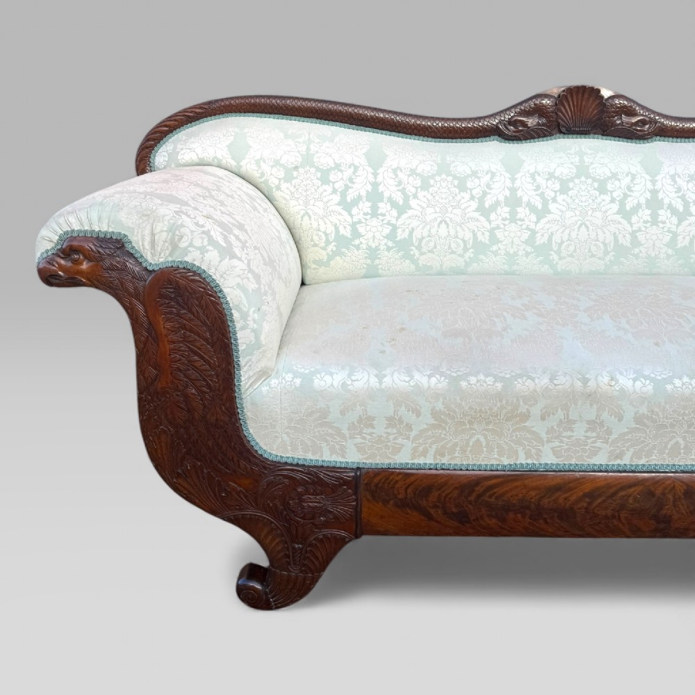 A nineteenth-century French Empire flame mahogany sofa featuring carved scroll arms, a serpentine crest, and light blue damask fabric upholstery. View V