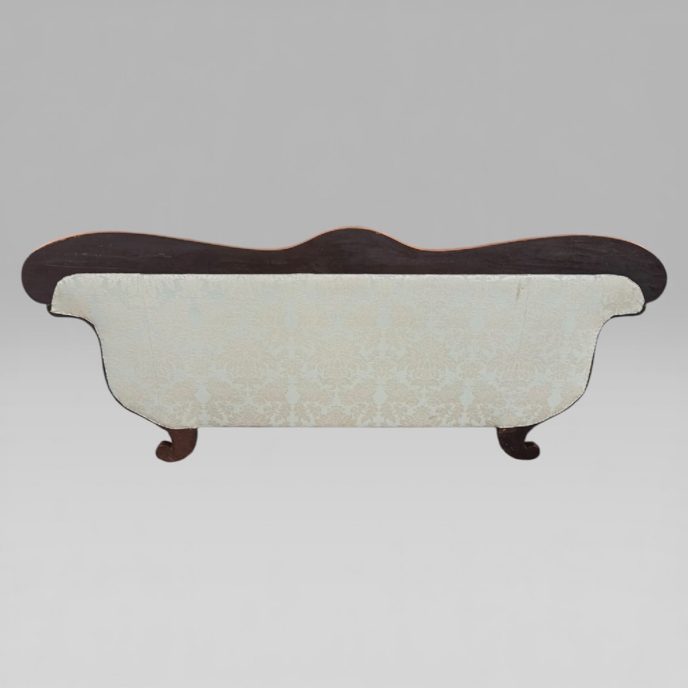 A nineteenth-century French Empire flame mahogany sofa featuring carved scroll arms, a serpentine crest, and light blue damask fabric upholstery. View IX