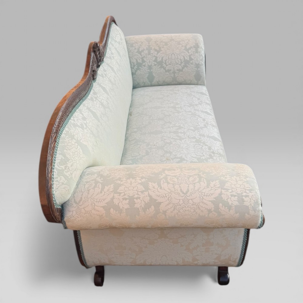 A nineteenth-century French Empire flame mahogany sofa featuring carved scroll arms, a serpentine crest, and light blue damask fabric upholstery. View XI