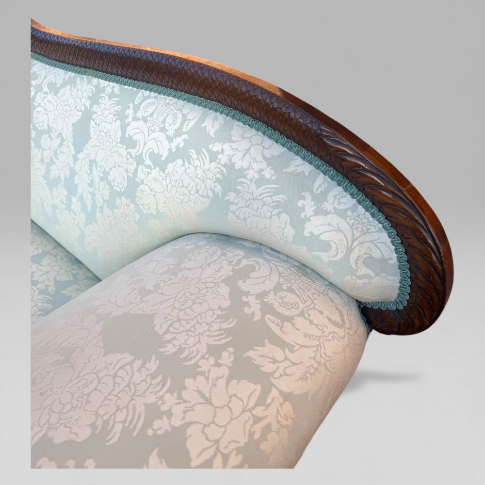 A nineteenth-century French Empire flame mahogany sofa featuring carved scroll arms, a serpentine crest, and light blue damask fabric upholstery. View XV