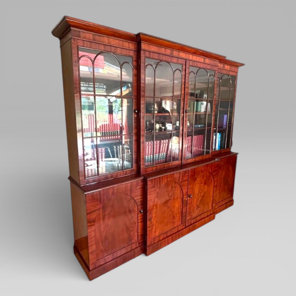 A large William IV flame mahogany breakfront library bookcase featuring four glazed upper doors with arched astragal glazing and four panelled cupboard doors beneath. View III