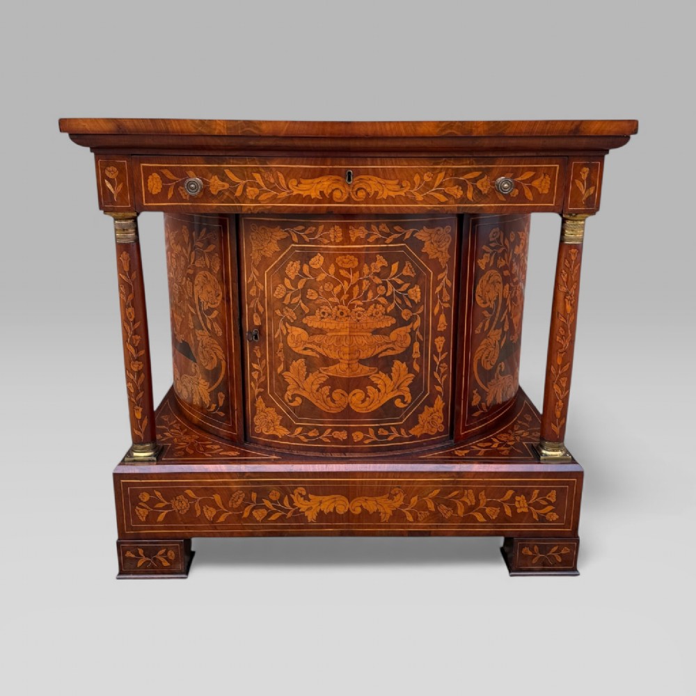 An 18th-century Dutch mahogany console table cabinet featuring detailed floral marquetry inlay, twin supporting columns, and a central cupboard door on a plinth base. View II