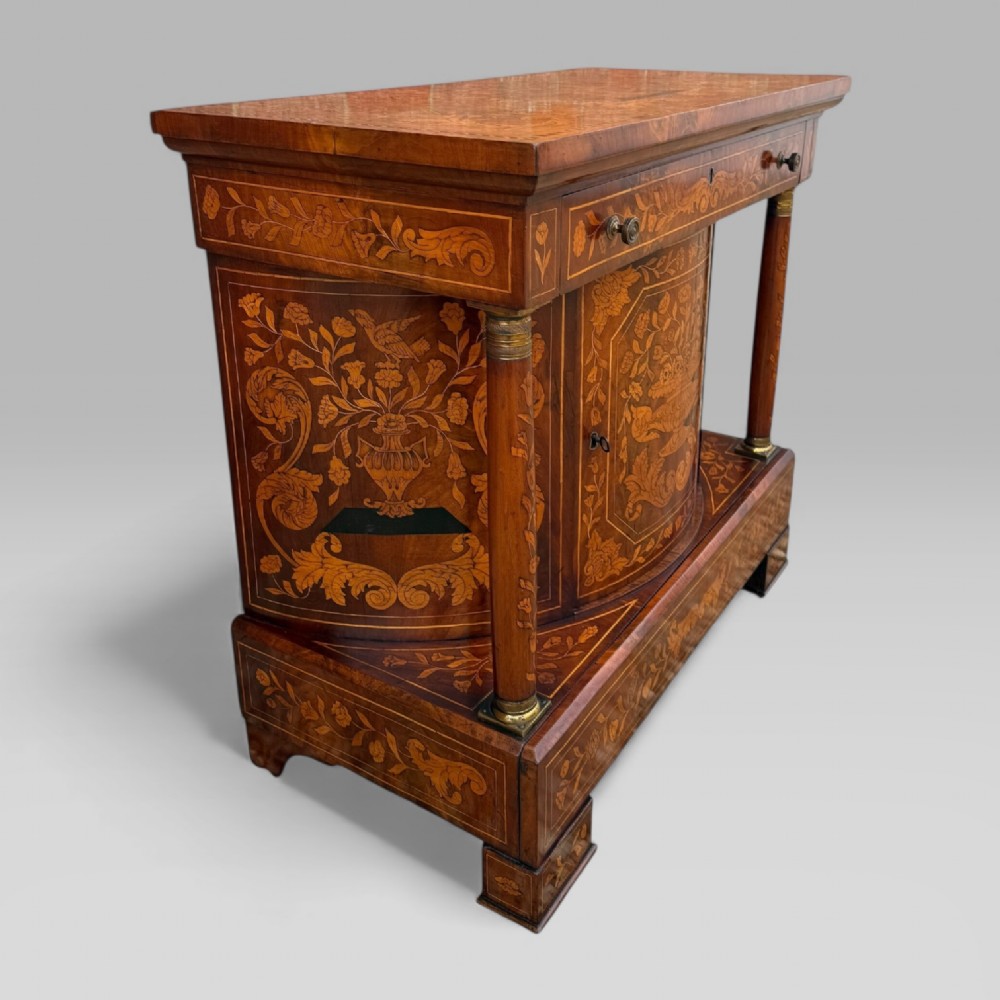 An 18th-century Dutch mahogany console table cabinet featuring detailed floral marquetry inlay, twin supporting columns, and a central cupboard door on a plinth base. View IV