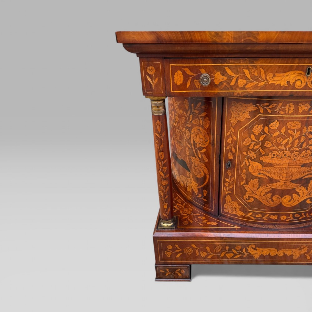 An 18th-century Dutch mahogany console table cabinet featuring detailed floral marquetry inlay, twin supporting columns, and a central cupboard door on a plinth base. View V