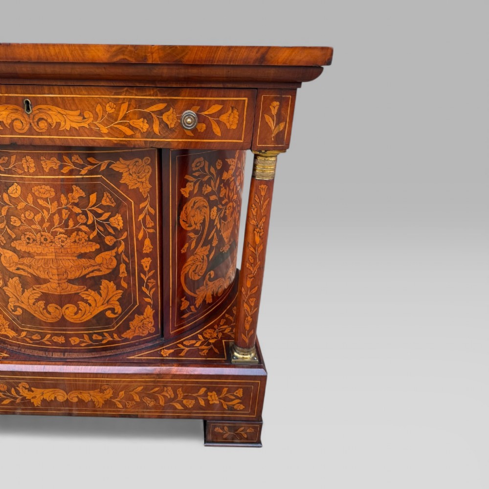 An 18th-century Dutch mahogany console table cabinet featuring detailed floral marquetry inlay, twin supporting columns, and a central cupboard door on a plinth base. View VI