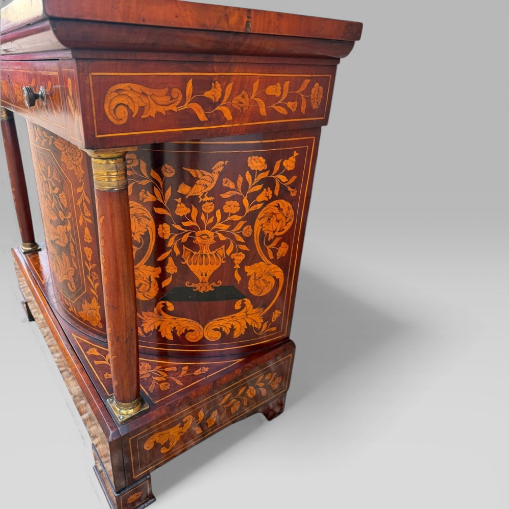An 18th-century Dutch mahogany console table cabinet featuring detailed floral marquetry inlay, twin supporting columns, and a central cupboard door on a plinth base. View X