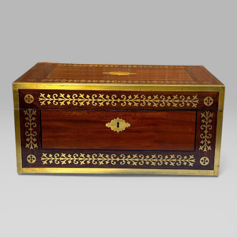 A rectangular dark timber writing slope featuring brass edge binding, intricate brass foliate inlay, a central brass nameplate, and a brass keyhole escutcheon. View II