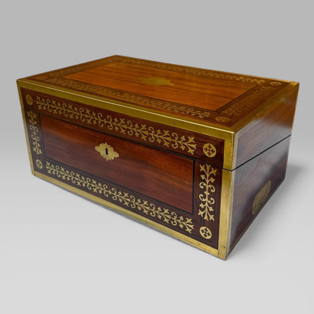 A rectangular dark timber writing slope featuring brass edge binding, intricate brass foliate inlay, a central brass nameplate, and a brass keyhole escutcheon. View III