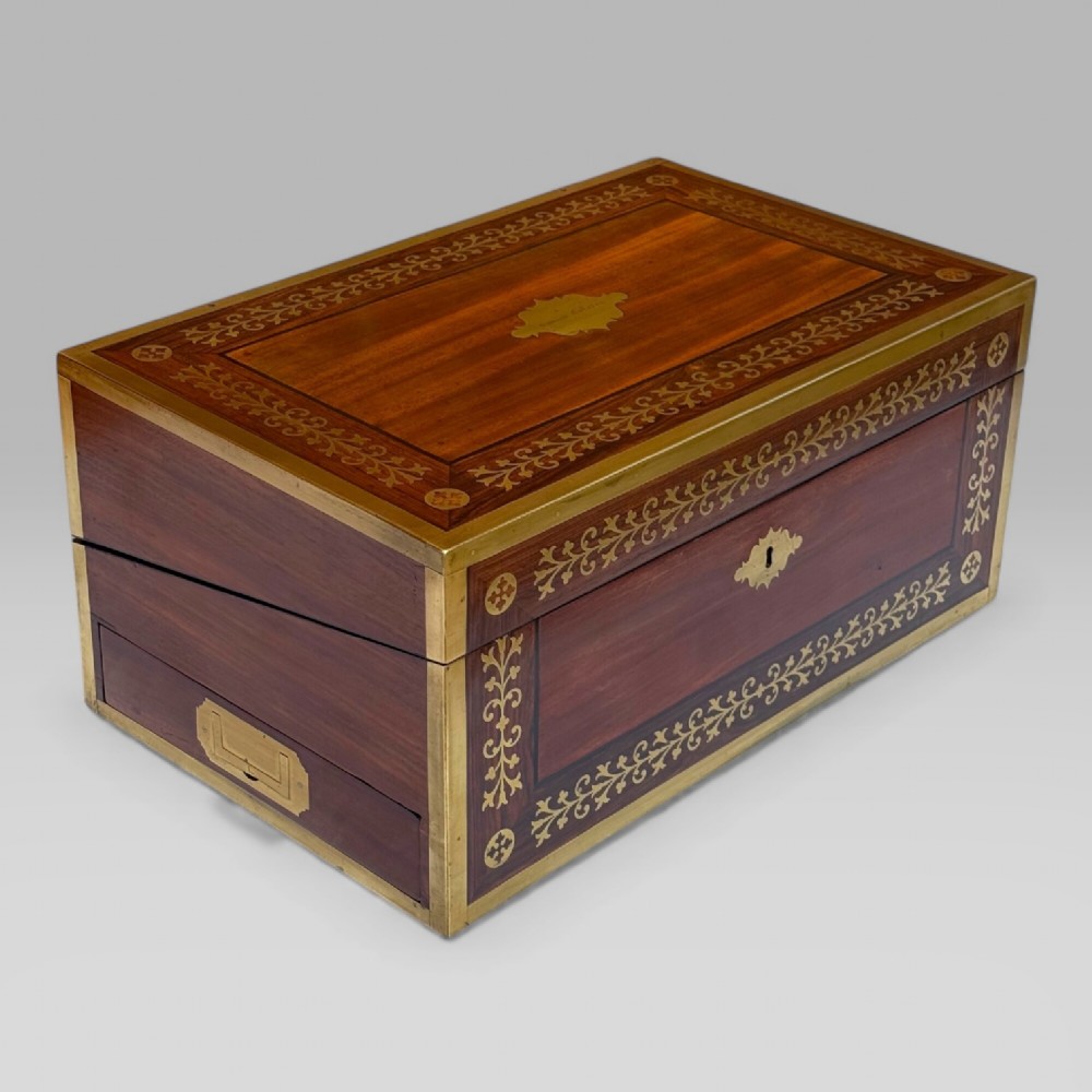 A rectangular dark timber writing slope featuring brass edge binding, intricate brass foliate inlay, a central brass nameplate, and a brass keyhole escutcheon. View IV