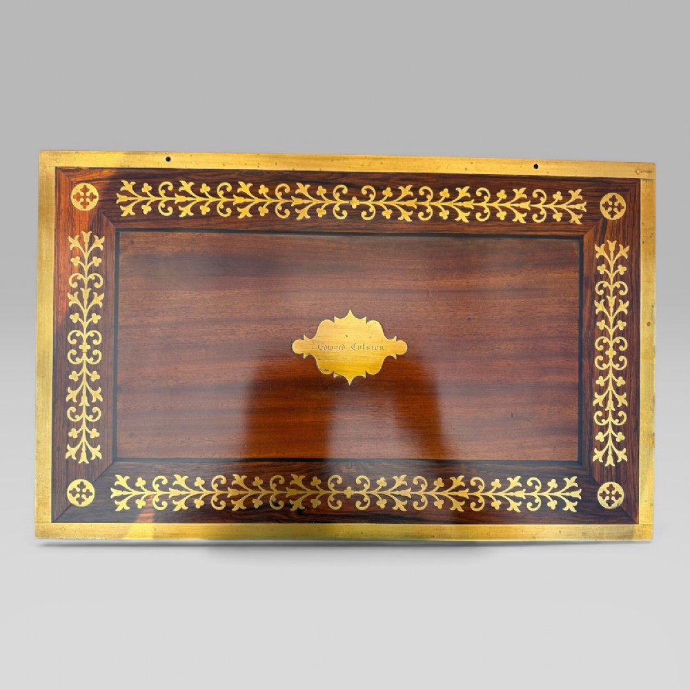 A rectangular dark timber writing slope featuring brass edge binding, intricate brass foliate inlay, a central brass nameplate, and a brass keyhole escutcheon. View VII