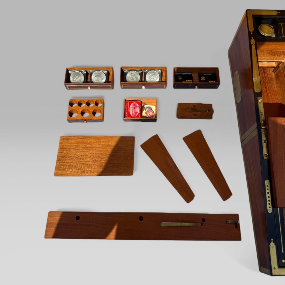 A rectangular dark timber writing slope featuring brass edge binding, intricate brass foliate inlay, a central brass nameplate, and a brass keyhole escutcheon. View XI