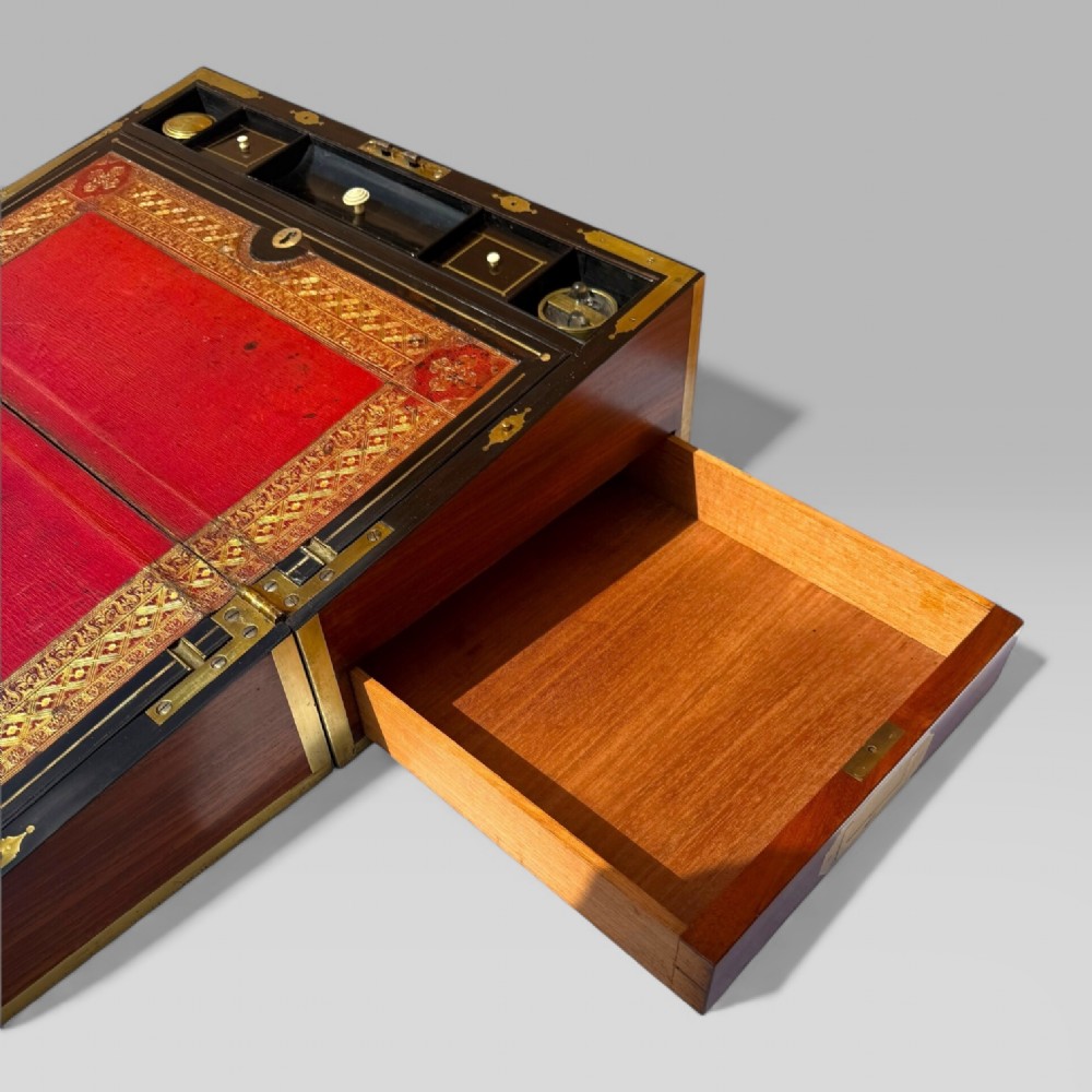 A rectangular dark timber writing slope featuring brass edge binding, intricate brass foliate inlay, a central brass nameplate, and a brass keyhole escutcheon. View XV