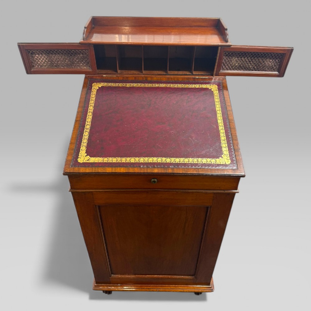 An antique mahogany Davenport desk featuring a sloped red leather writing surface, turned drawer knobs, and a top gallery superstructure. View V