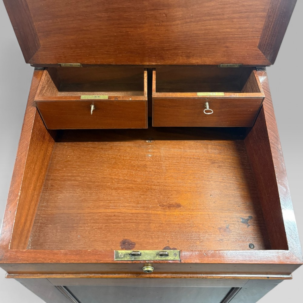 An antique mahogany Davenport desk featuring a sloped red leather writing surface, turned drawer knobs, and a top gallery superstructure. View VI