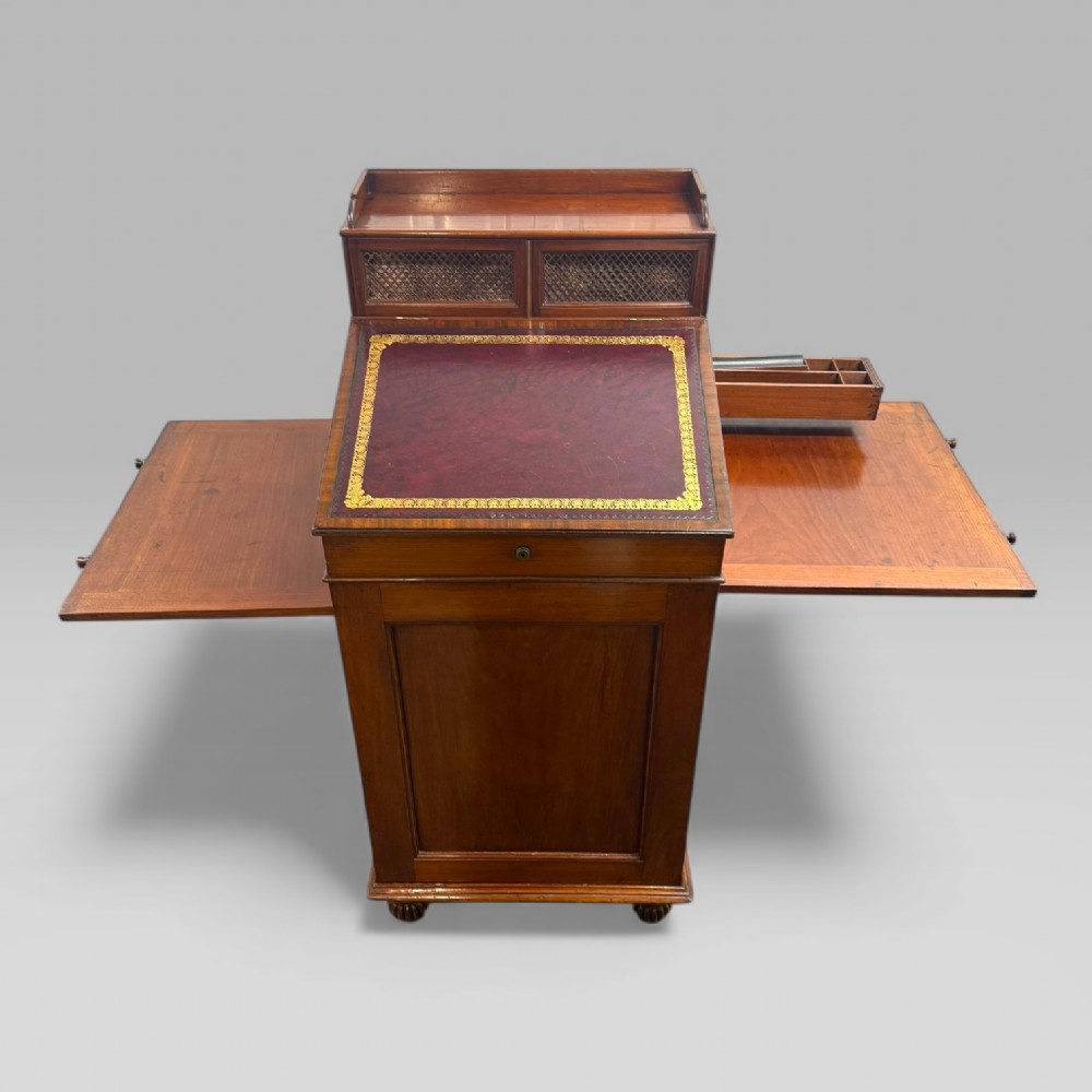 An antique mahogany Davenport desk featuring a sloped red leather writing surface, turned drawer knobs, and a top gallery superstructure. View VII