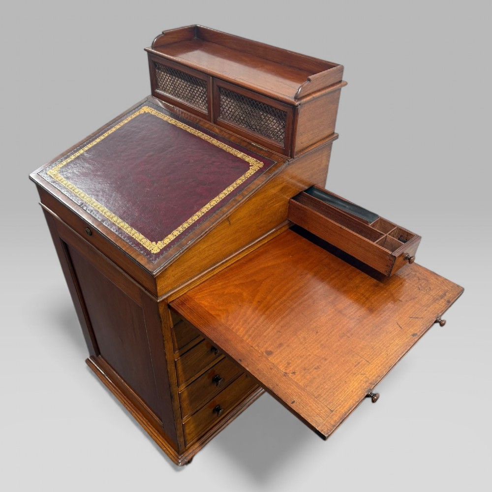 An antique mahogany Davenport desk featuring a sloped red leather writing surface, turned drawer knobs, and a top gallery superstructure. View VIII