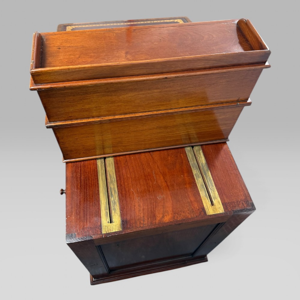 An antique mahogany Davenport desk featuring a sloped red leather writing surface, turned drawer knobs, and a top gallery superstructure. View XI