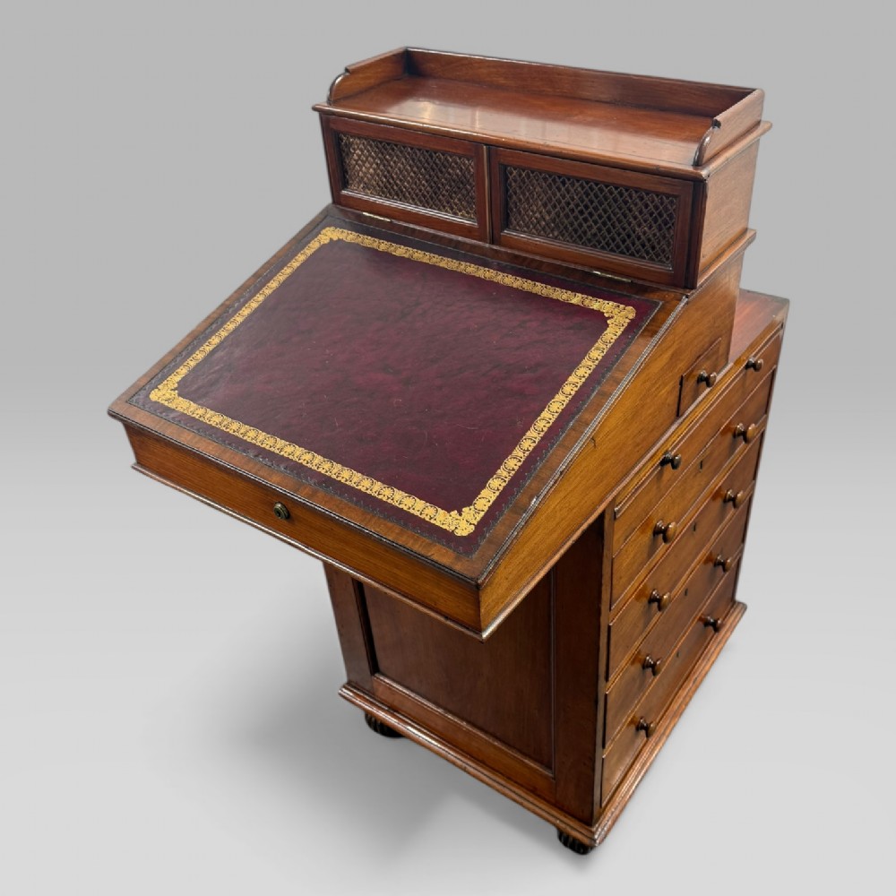 An antique mahogany Davenport desk featuring a sloped red leather writing surface, turned drawer knobs, and a top gallery superstructure. View XII