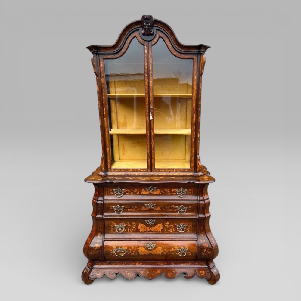 An antique walnut display cabinet on a bombe chest of drawers featuring floral marquetry inlay, glazed doors, and brass handles. View II