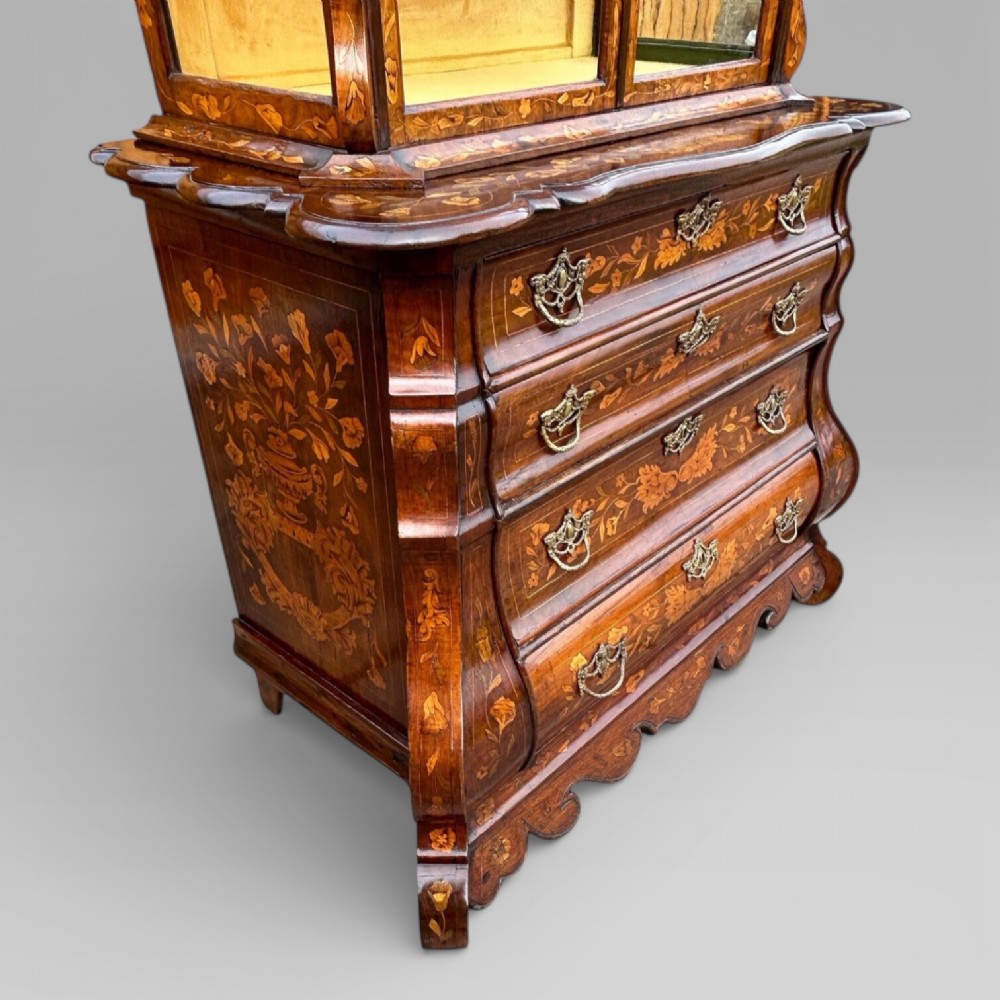 An antique walnut display cabinet on a bombe chest of drawers featuring floral marquetry inlay, glazed doors, and brass handles. View VIII