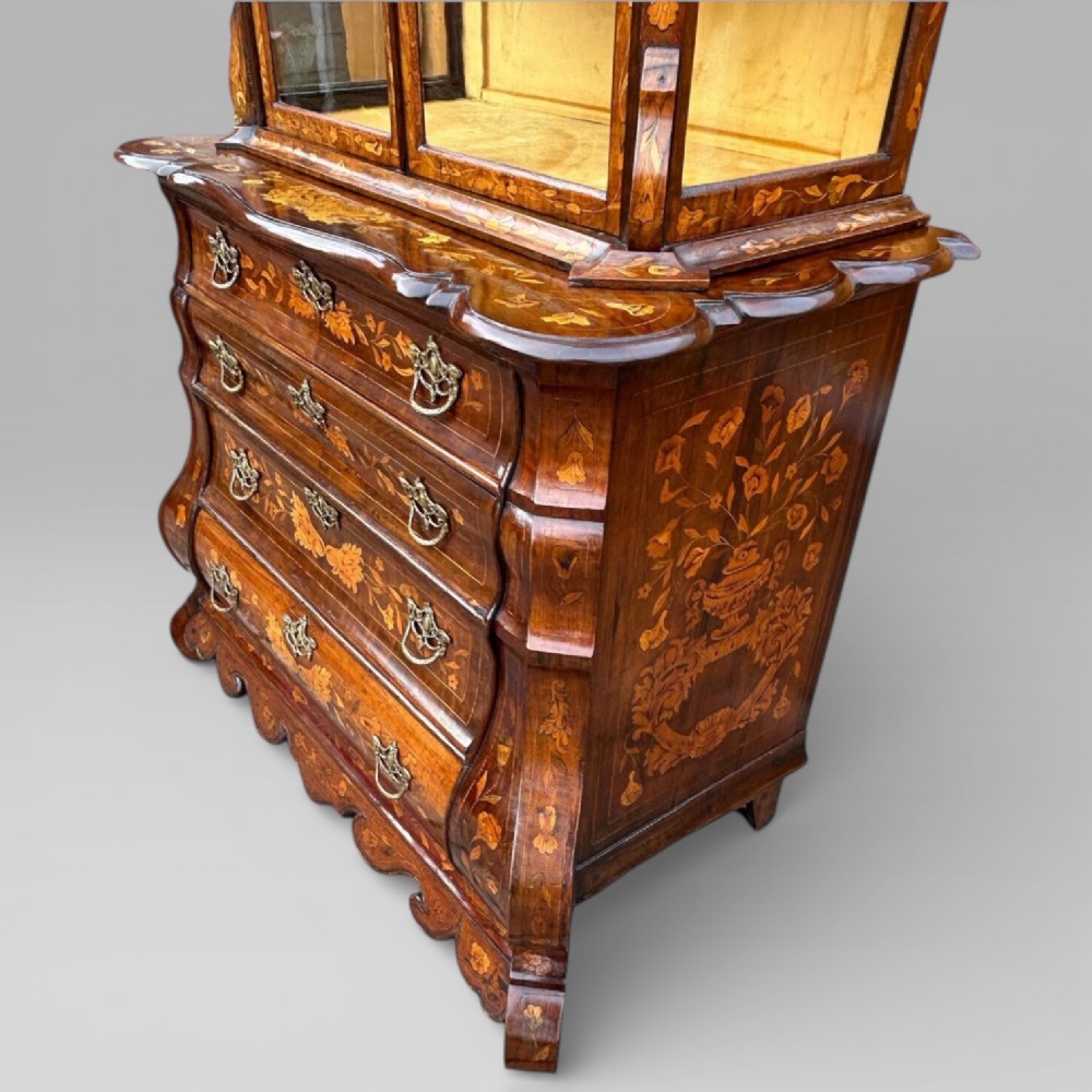 An antique walnut display cabinet on a bombe chest of drawers featuring floral marquetry inlay, glazed doors, and brass handles. View XI