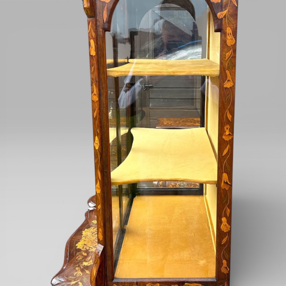 An antique walnut display cabinet on a bombe chest of drawers featuring floral marquetry inlay, glazed doors, and brass handles. View XIII