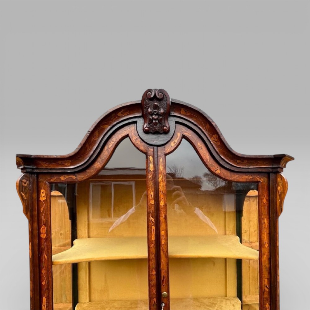 An antique walnut display cabinet on a bombe chest of drawers featuring floral marquetry inlay, glazed doors, and brass handles. View XIV