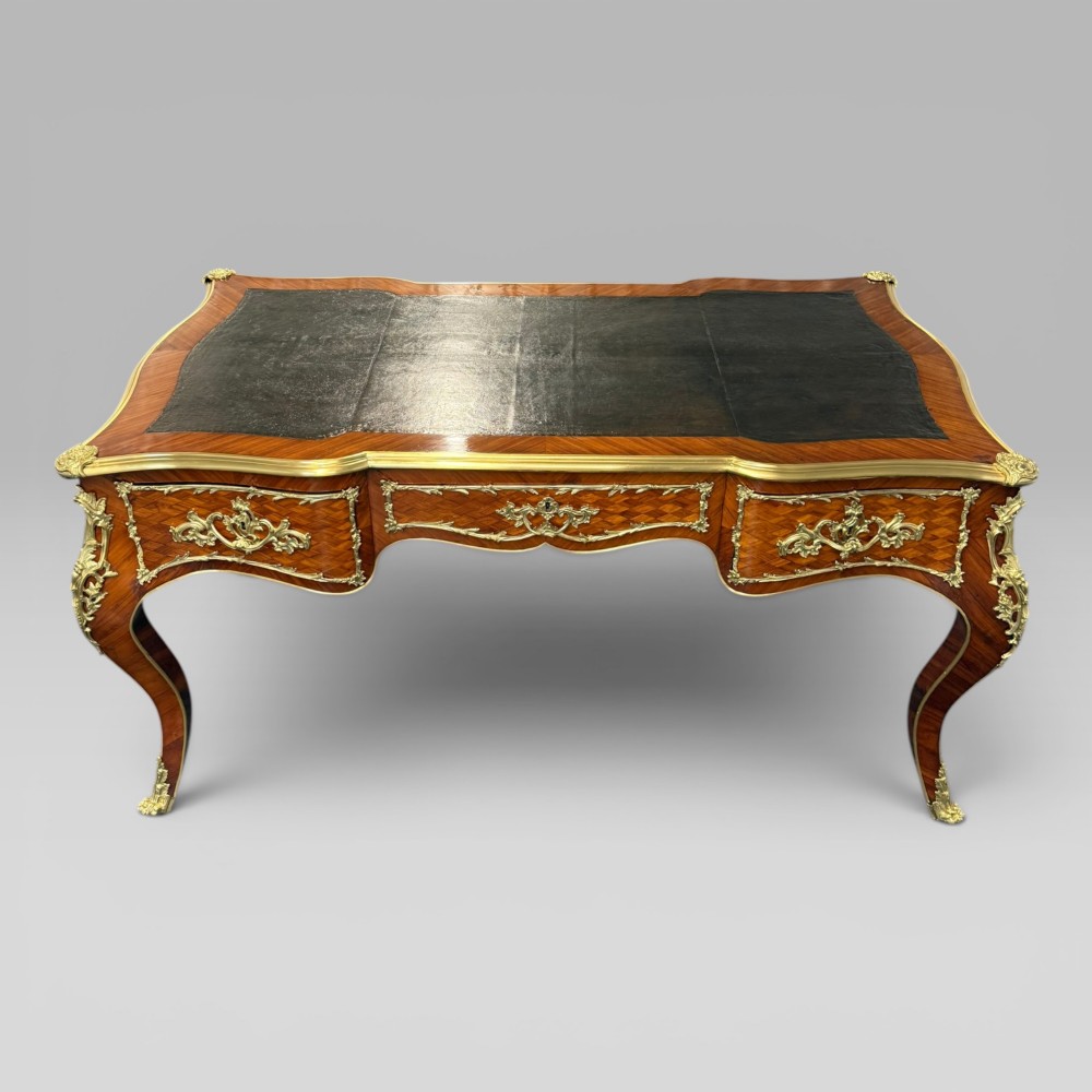 A Louis XV style kingwood parquetry bureau plat featuring a dark leather writing surface, cabriole legs, and gilt-bronze ormolu mounts. View II