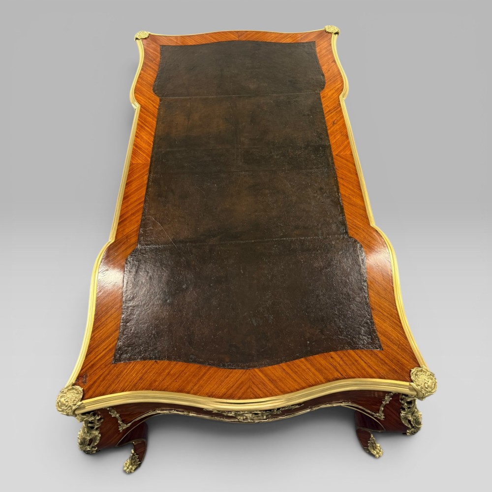 A Louis XV style kingwood parquetry bureau plat featuring a dark leather writing surface, cabriole legs, and gilt-bronze ormolu mounts. View VIII
