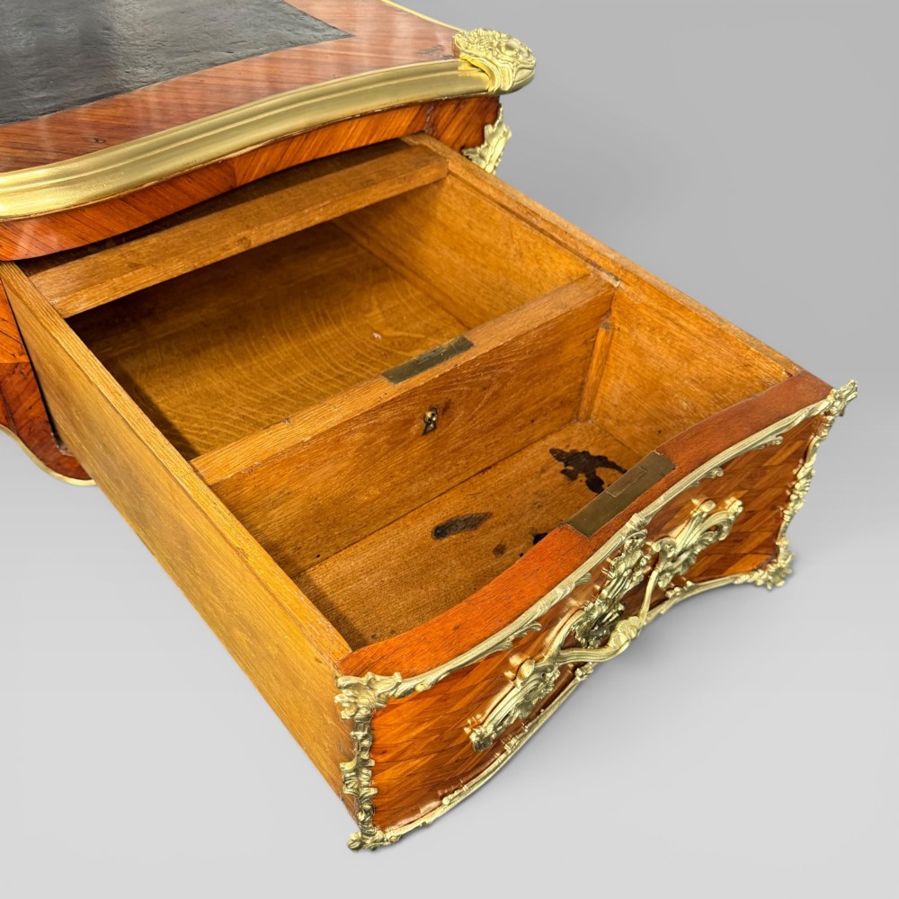 A Louis XV style kingwood parquetry bureau plat featuring a dark leather writing surface, cabriole legs, and gilt-bronze ormolu mounts. View IX
