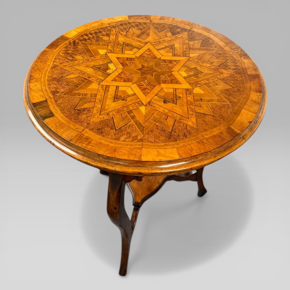 A circular antique side table featuring an intricate multi-timber geometric starburst marquetry pattern on top, set on carved cabriole legs with a triangular lower tier. View IV