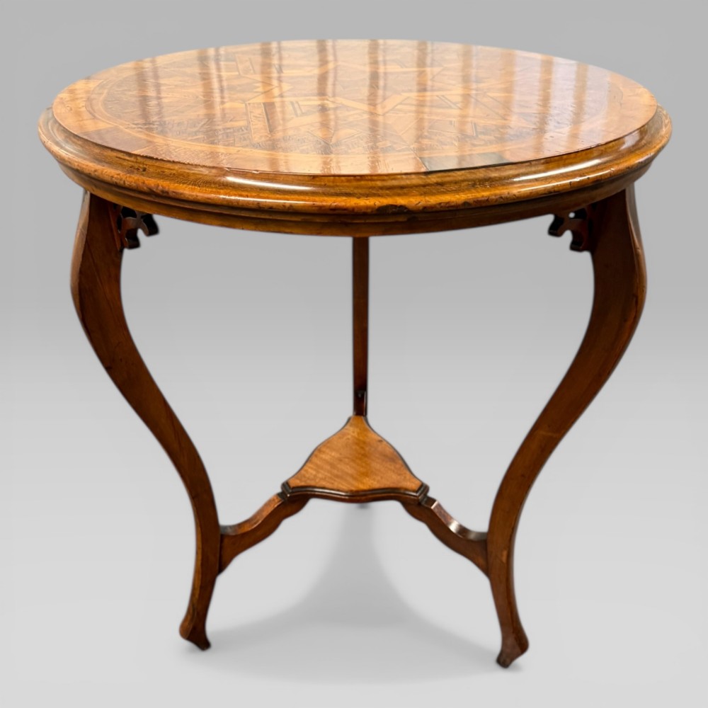 A circular antique side table featuring an intricate multi-timber geometric starburst marquetry pattern on top, set on carved cabriole legs with a triangular lower tier. View VII