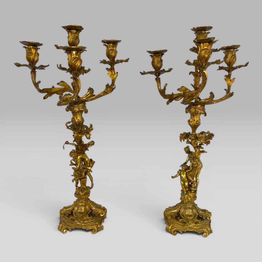 A pair of late nineteenth-century French Rococo gilt bronze candelabra with figural stems, scrolling floral arms, and ornate bases.