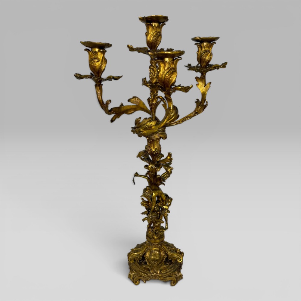 A pair of late nineteenth-century French Rococo gilt bronze candelabra with figural stems, scrolling floral arms, and ornate bases. View II