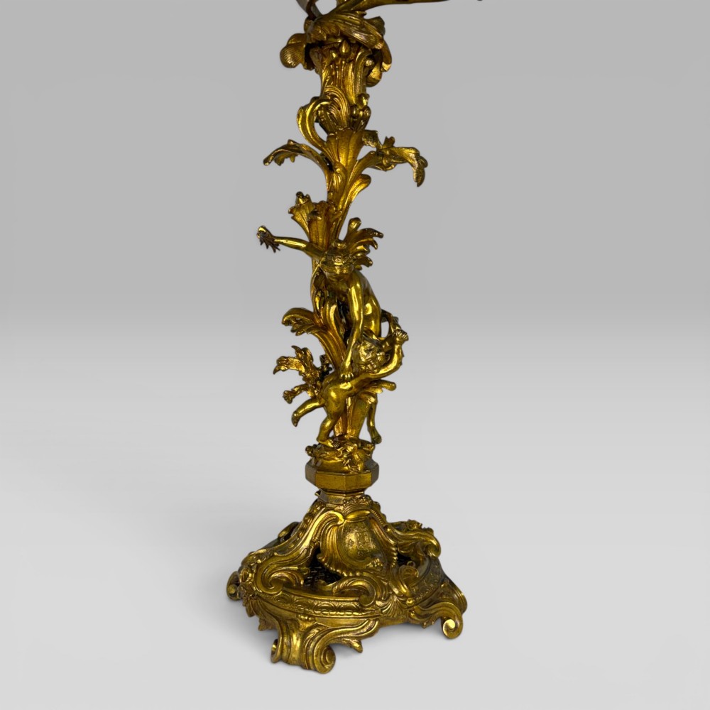 A pair of late nineteenth-century French Rococo gilt bronze candelabra with figural stems, scrolling floral arms, and ornate bases. View V