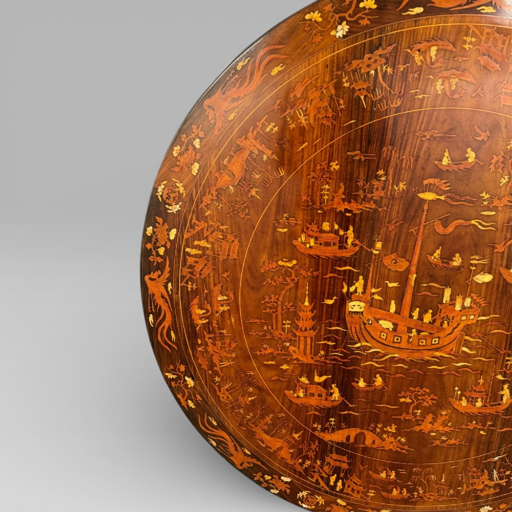 Circular rosewood centre table featuring detailed marquetry depictions of ships, pagodas, and floral motifs resting on a square inlaid pedestal base. View IV