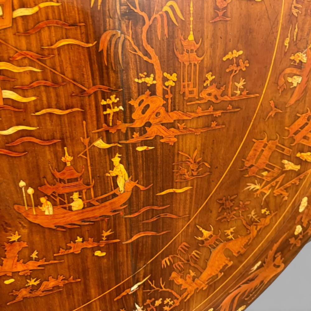 Circular rosewood centre table featuring detailed marquetry depictions of ships, pagodas, and floral motifs resting on a square inlaid pedestal base. View VIII