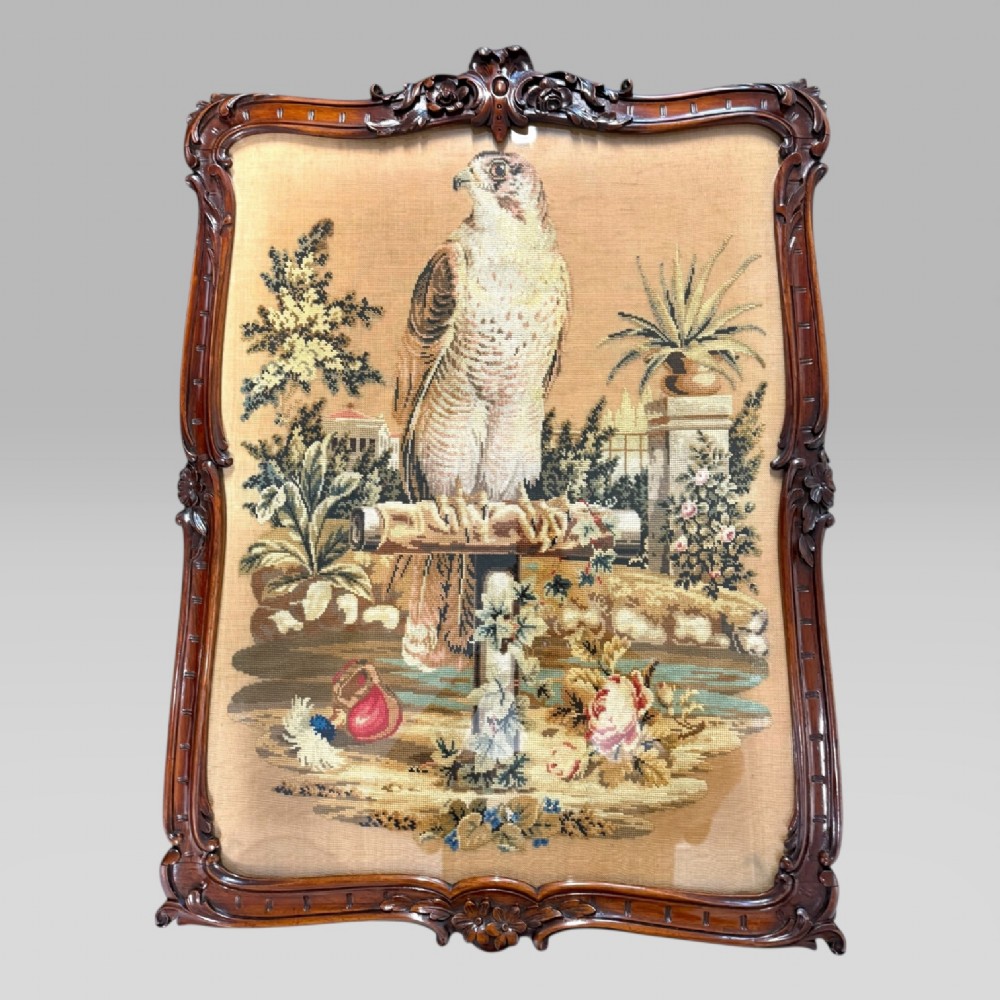 A William IV rosewood tilt-top tripod table featuring a shaped, carved frame housing a glazed needlepoint panel above a carved column and splayed tripod legs. View IV