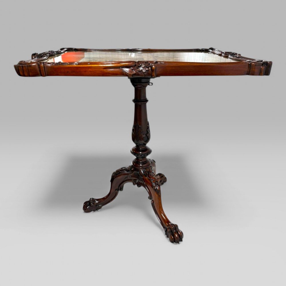 A William IV rosewood tilt-top tripod table featuring a shaped, carved frame housing a glazed needlepoint panel above a carved column and splayed tripod legs. View VIII
