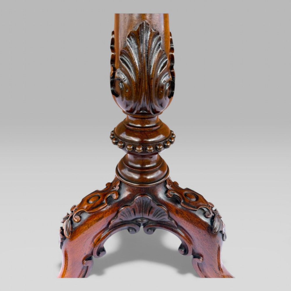 A William IV rosewood tilt-top tripod table featuring a shaped, carved frame housing a glazed needlepoint panel above a carved column and splayed tripod legs. View XIII