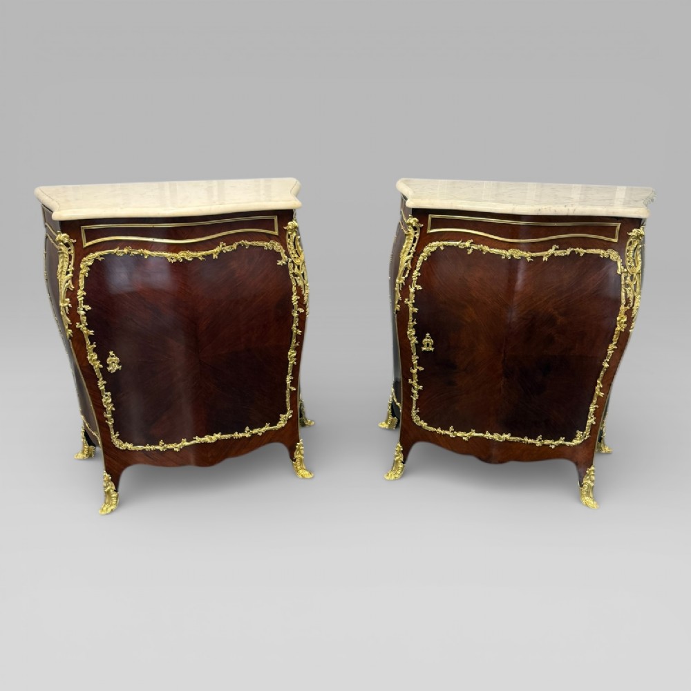 A pair of late 19th-century French kingwood bombe cabinets featuring ornate gilt-bronze mounts, curved fronts, and pale marble tops. View II