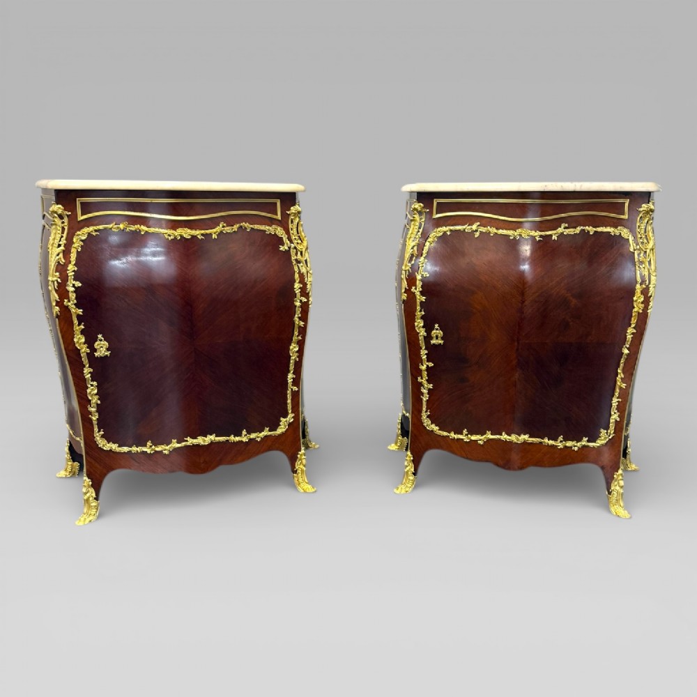 A pair of late 19th-century French kingwood bombe cabinets featuring ornate gilt-bronze mounts, curved fronts, and pale marble tops. View IV