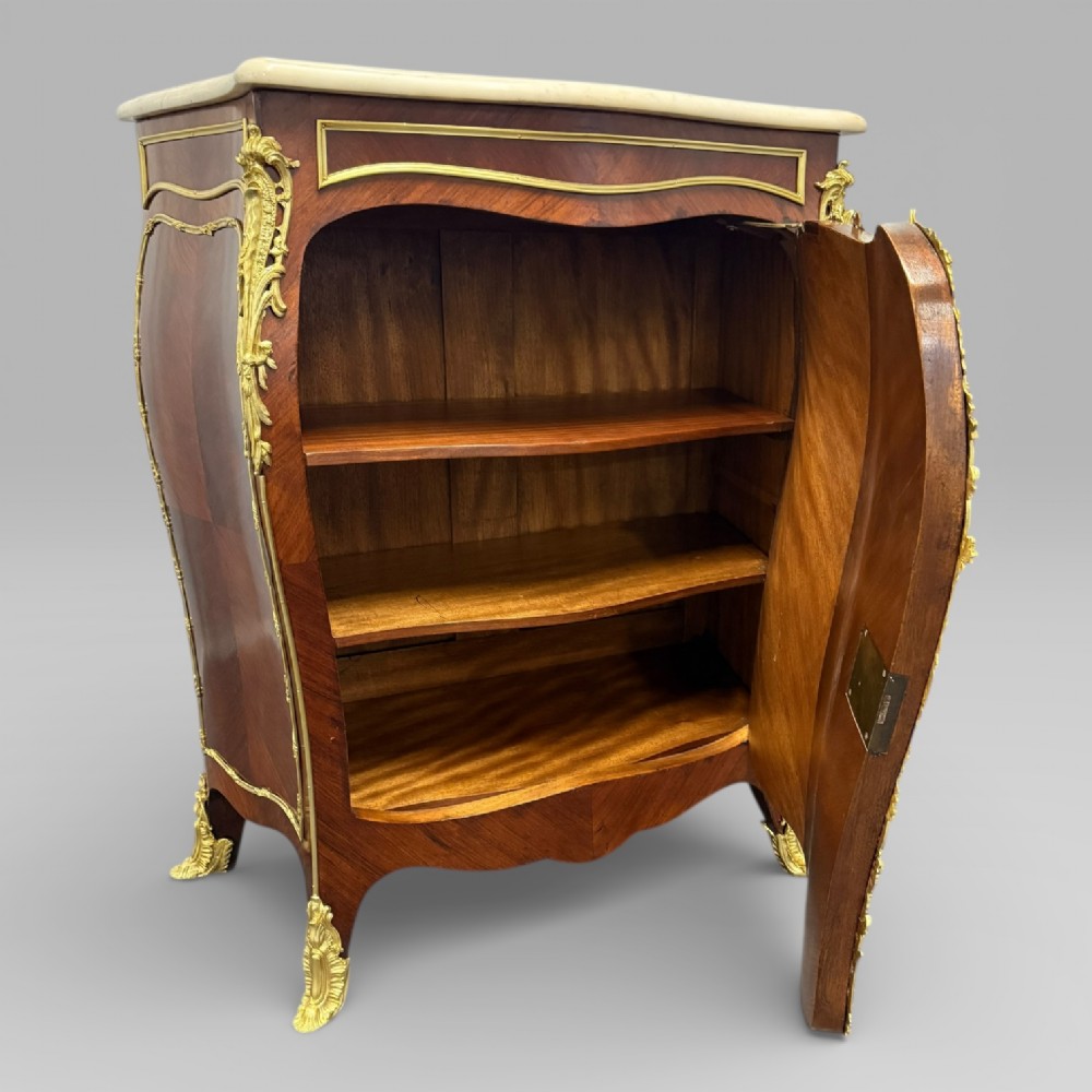 A pair of late 19th-century French kingwood bombe cabinets featuring ornate gilt-bronze mounts, curved fronts, and pale marble tops. View VIII