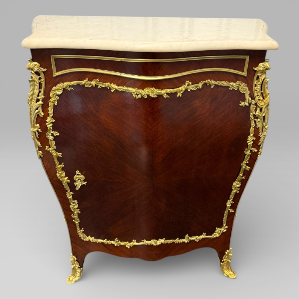 A pair of late 19th-century French kingwood bombe cabinets featuring ornate gilt-bronze mounts, curved fronts, and pale marble tops. View IX