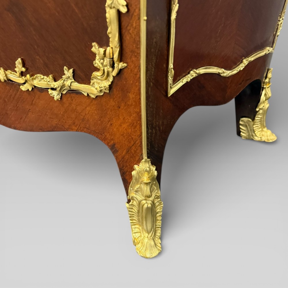 A pair of late 19th-century French kingwood bombe cabinets featuring ornate gilt-bronze mounts, curved fronts, and pale marble tops. View X