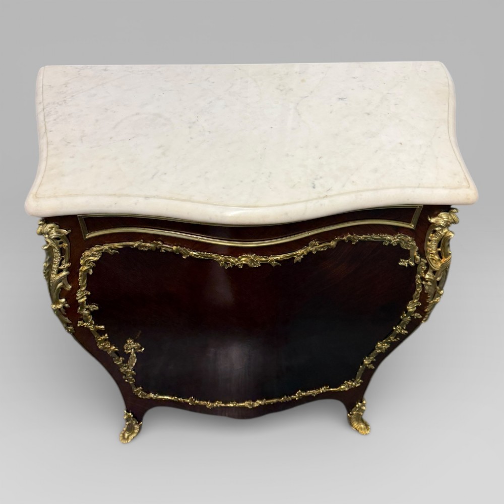 A pair of late 19th-century French kingwood bombe cabinets featuring ornate gilt-bronze mounts, curved fronts, and pale marble tops. View XI