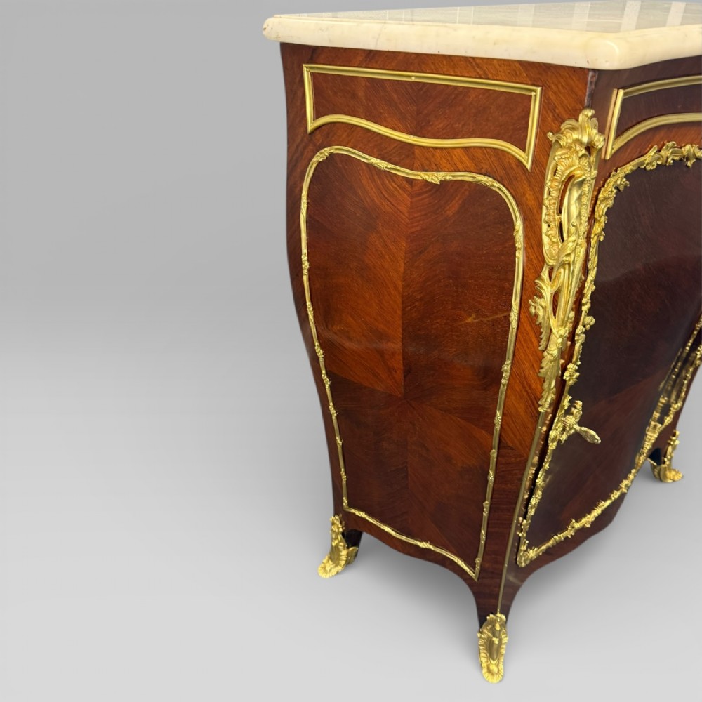 A pair of late 19th-century French kingwood bombe cabinets featuring ornate gilt-bronze mounts, curved fronts, and pale marble tops. View XII