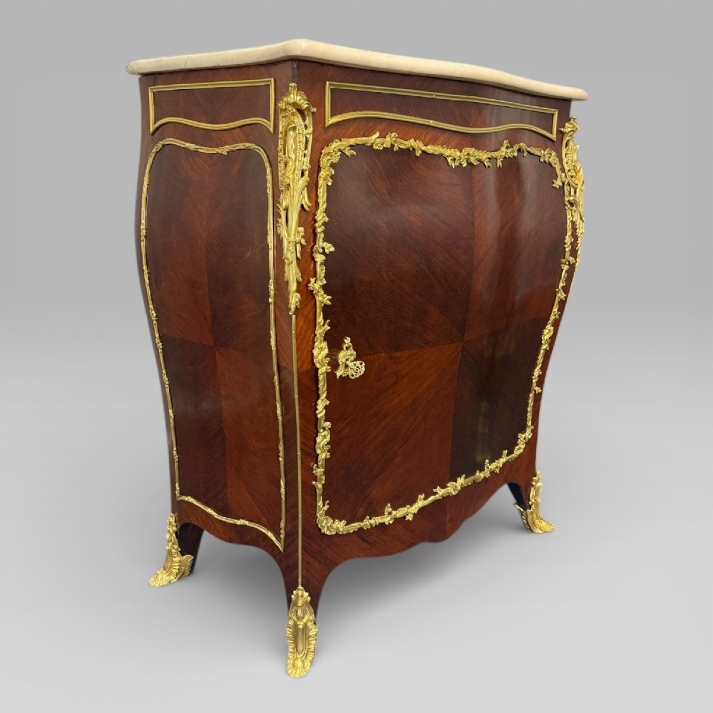 A pair of late 19th-century French kingwood bombe cabinets featuring ornate gilt-bronze mounts, curved fronts, and pale marble tops. View XIII