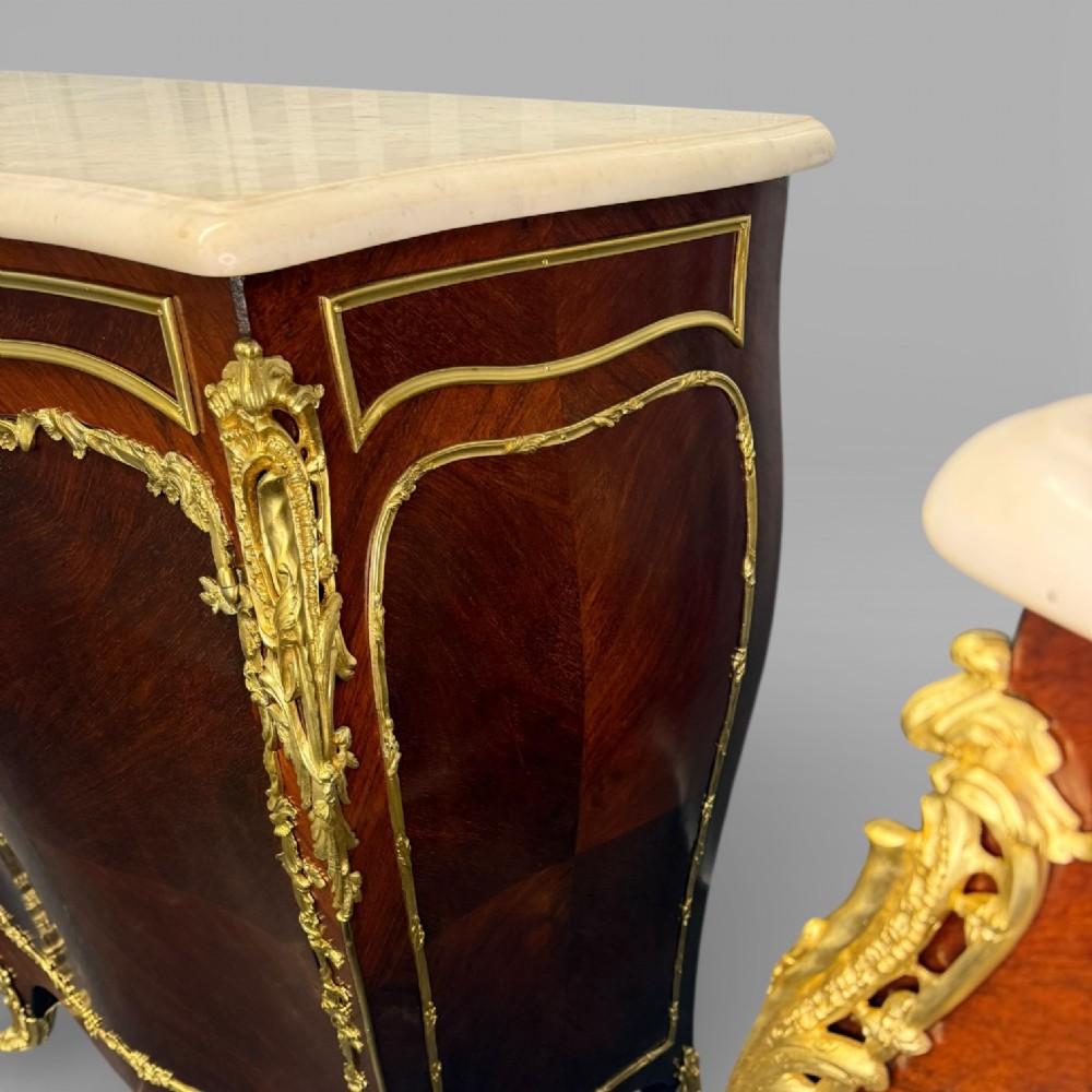 A pair of late 19th-century French kingwood bombe cabinets featuring ornate gilt-bronze mounts, curved fronts, and pale marble tops. View XIV