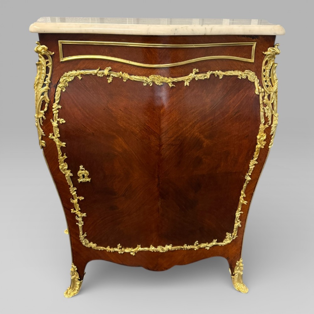 A pair of late 19th-century French kingwood bombe cabinets featuring ornate gilt-bronze mounts, curved fronts, and pale marble tops. View XV